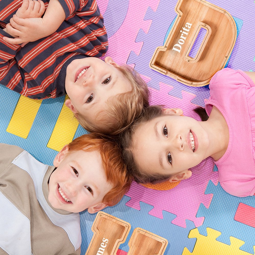 Happy children playing with their custom Summidate wooden letter piggy banks on a colorful playmat, a top-rated educational holiday gift in Australia.
