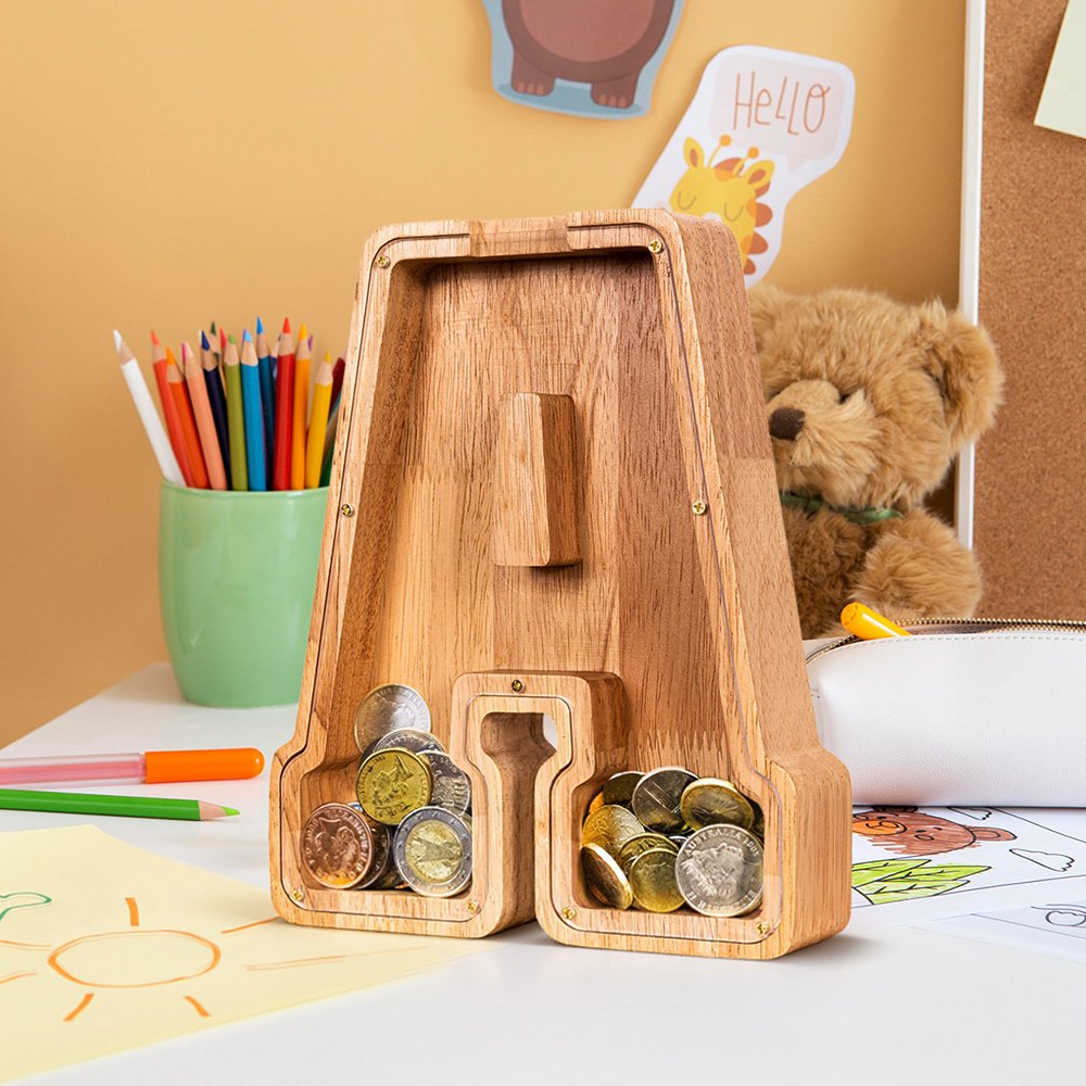 Eco-friendly Summidate wooden letter A piggy bank filled with coins on a child's desk, a great educational gift for learning to save in the USA.
