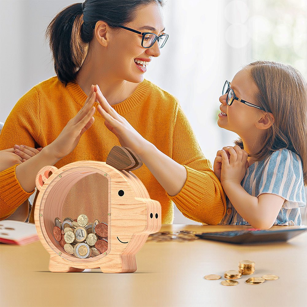 A mother and daughter happily counting coins together with their natural wood piggy bank on the desk. A great tool for teaching financial literacy and building family savings habits.