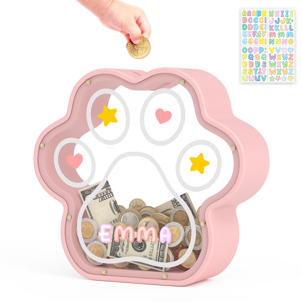Hand dropping a coin into a pink personalized paw piggy bank, colorful alphabet stickers included for kids DIY.