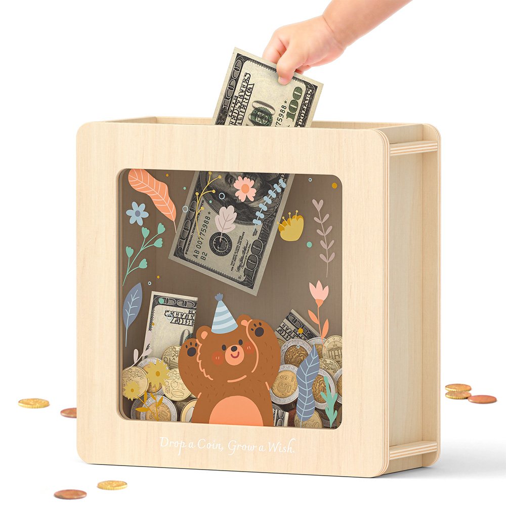 Inserting a folded dollar bill into a classic natural wood piggy bank with a clear acrylic front and adorable bear design.