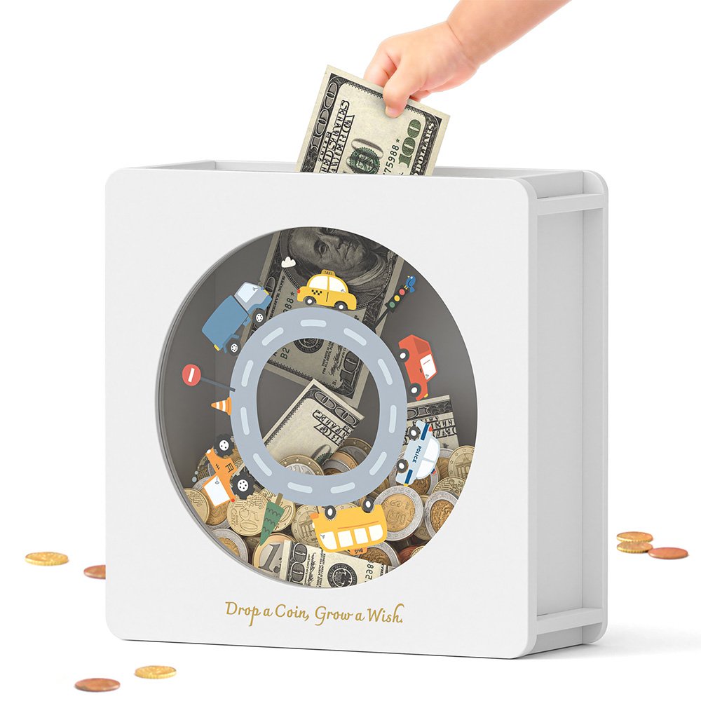 A hand inserting folded paper money into the top slot of the white wooden cash savings bank featuring a cute car track design.